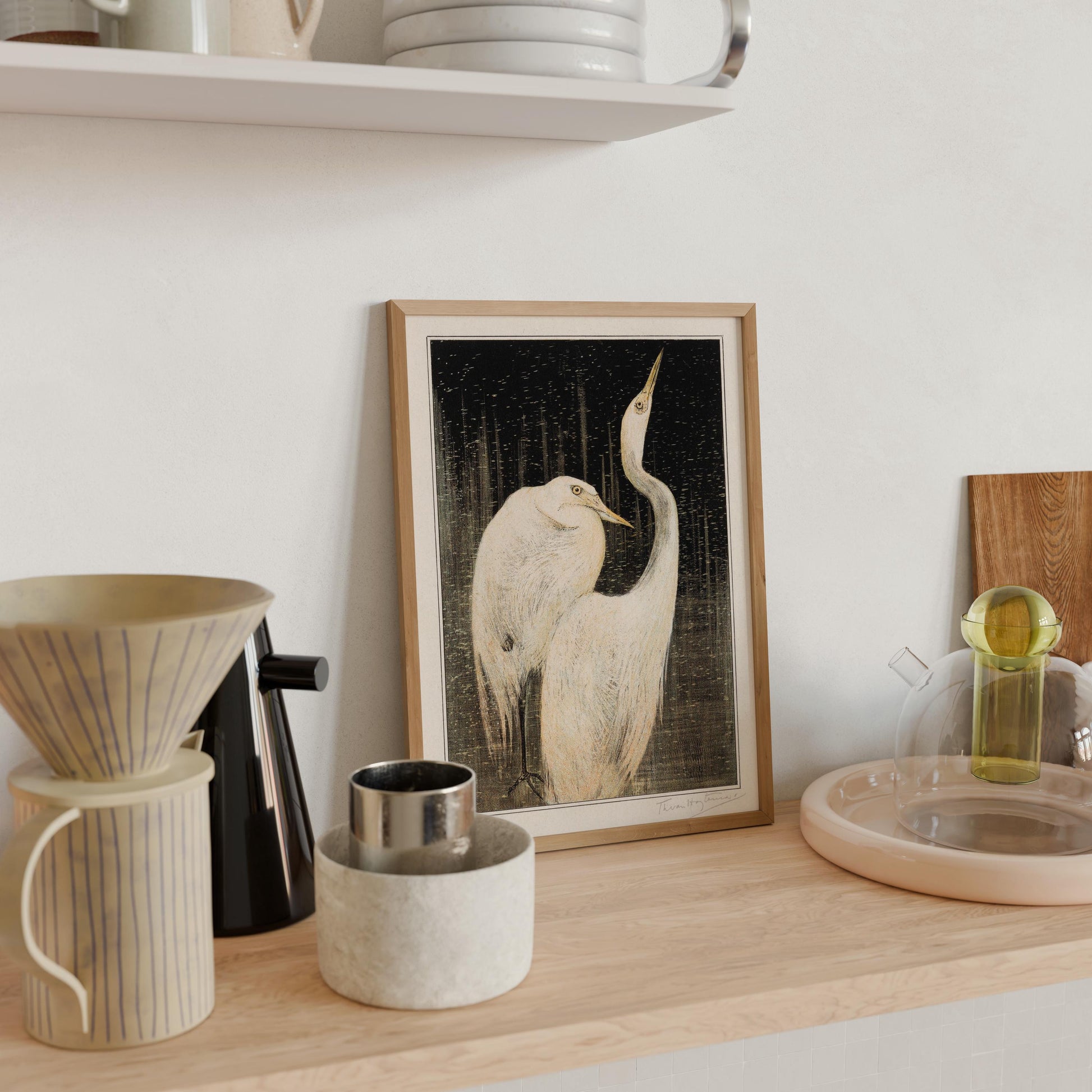 a wooden shelf with various objects, including a framed picture of two white birds, a coffee maker, a glass container, and a ceramic vase.